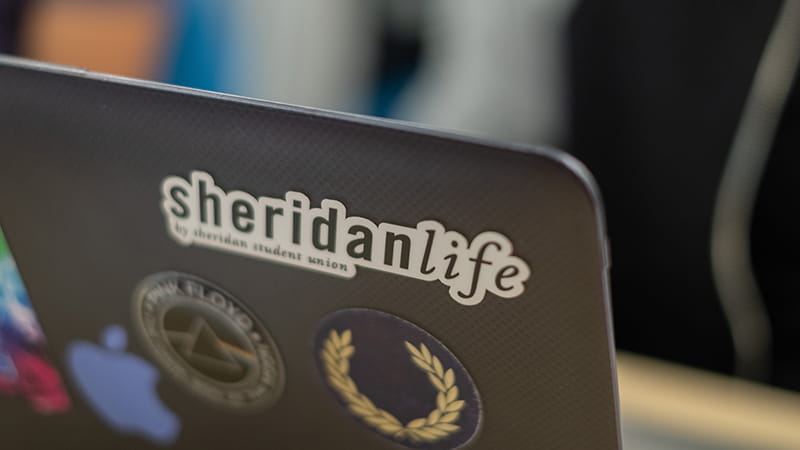 Close-up of laptop lid with a Sheridan life sticker on it