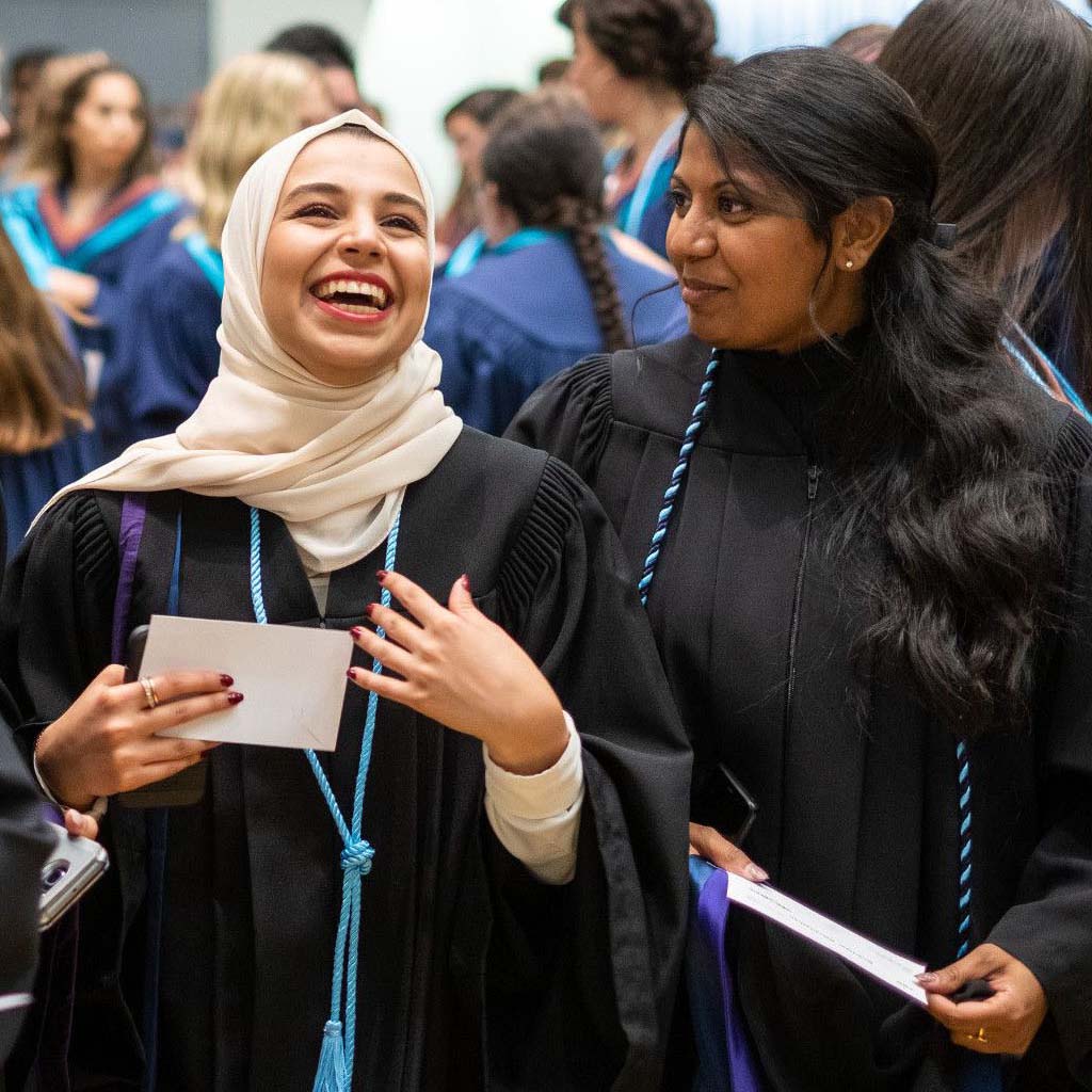 Two graduates smiling in their gowns