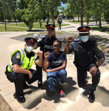 Stephanie Garrick (centre) kneeling with members of the Peel Regional Police at the Sheridan Black Students Association solidarity march