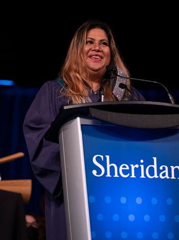 Meena Chowdhury speaking at the podium during her convocation ceremony.