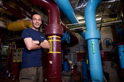 Roger Robelo standing arms crossed in a building maintenance room