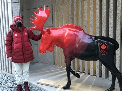 Brian Cheeseman standing next to Canada's fibreglass moose mascot in the Olympic athletes village in Beijing