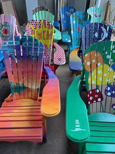 Colourful Muskoka chairs designed and painted by Sheridan students lined up in pairs.