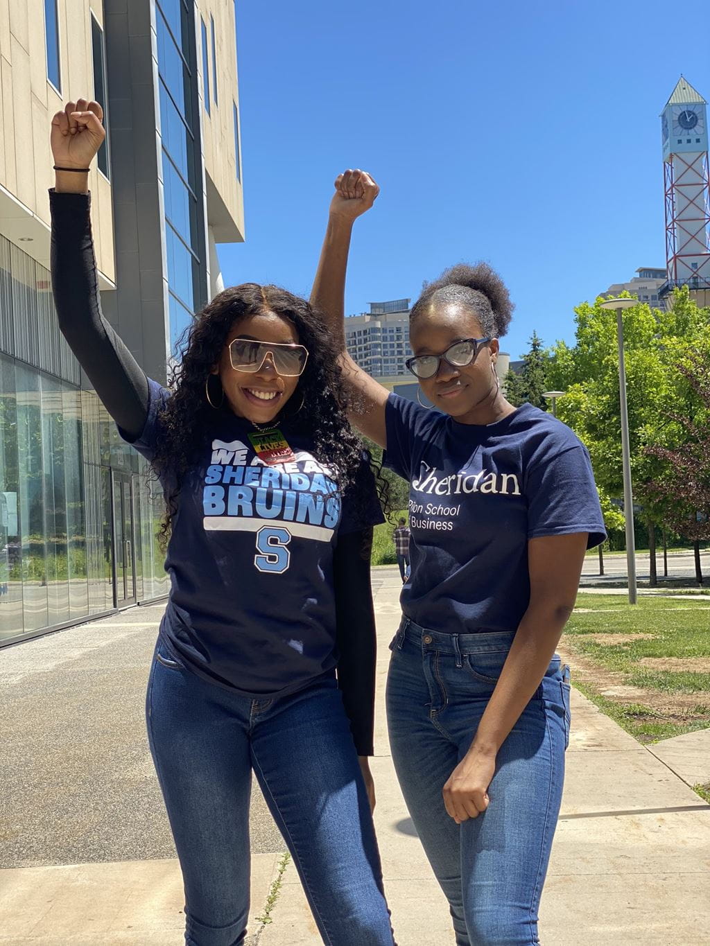 Two students from the Sheridan Black Students Association standing with their right arms raised in the air.