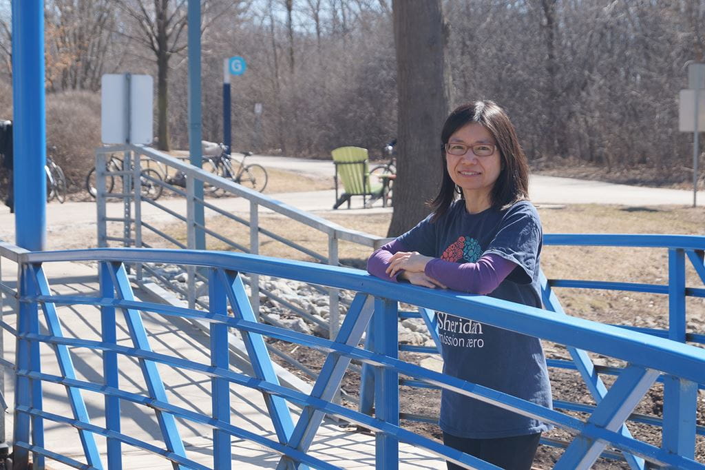 Wai Chu Cheng leaning against a blue bridge at Trafalgar Campus