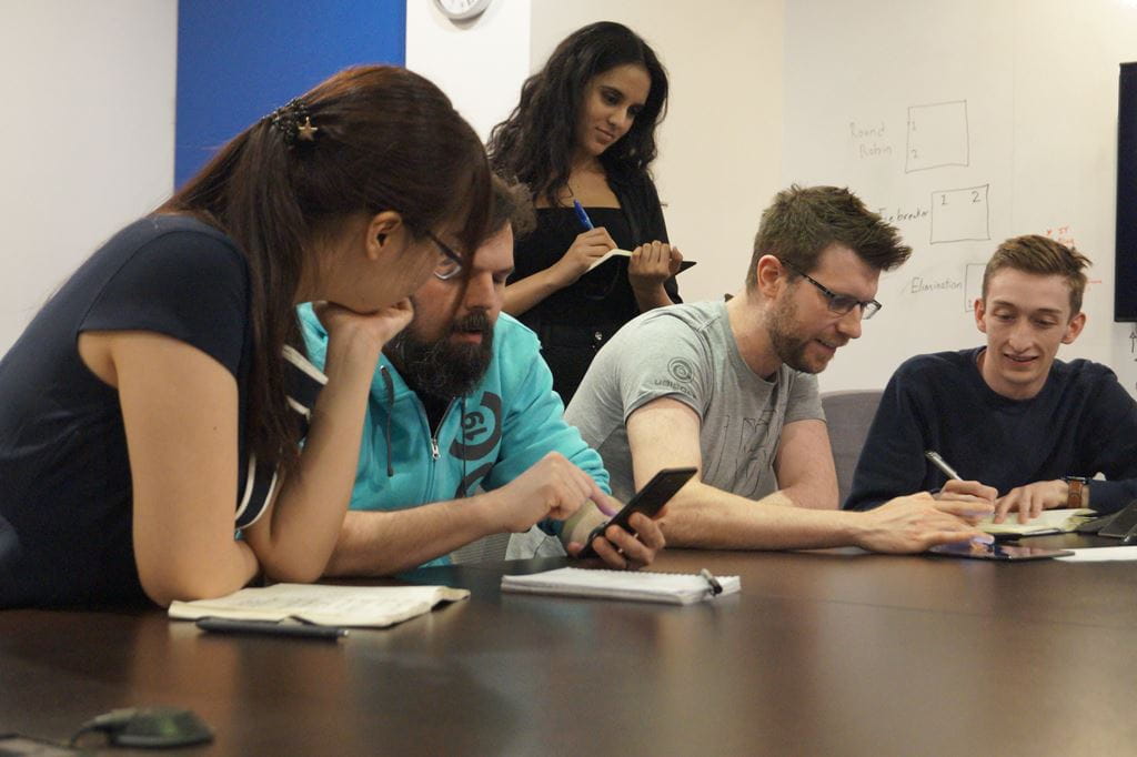 Group of students and Ubisoft developers looking at a game on a mobile device