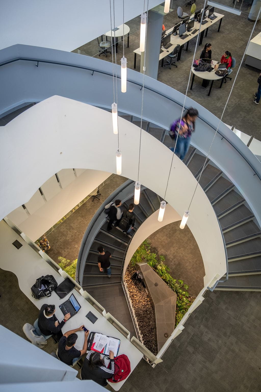 Student walking down a spiral staircase at Sheridan's Davis Campus Library