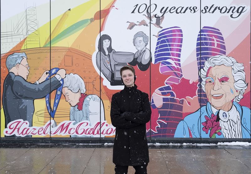 Jude Phillips standing in front of the mural he designed for Hazel McCallion