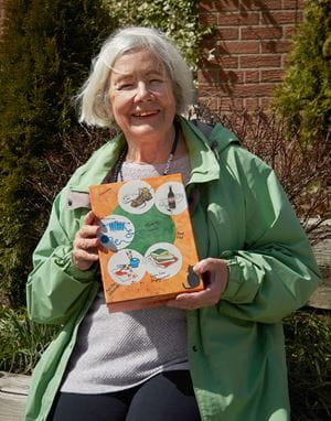 An older woman holds up a box covered with drawings of things that are key to a good memory