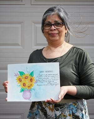 An older woman holds a painting she created titled 'Sunny Memories' and featuring a bouquet of flowers