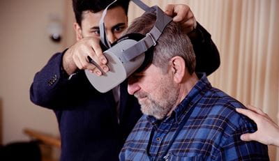 Researcher places a VR headset on an adult participant
