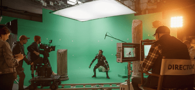 A camera crew films a character on a virtual production set while the director watches