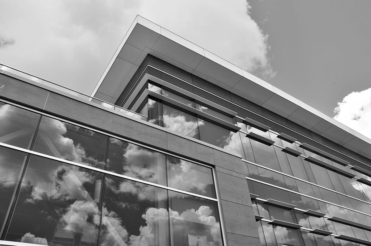 Grayscale image of the upper portion of a campus building with clouds and sky