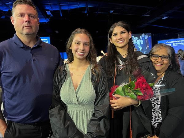 Mikaela Delaney poses with her sister and parents while holding a bunch of red roses